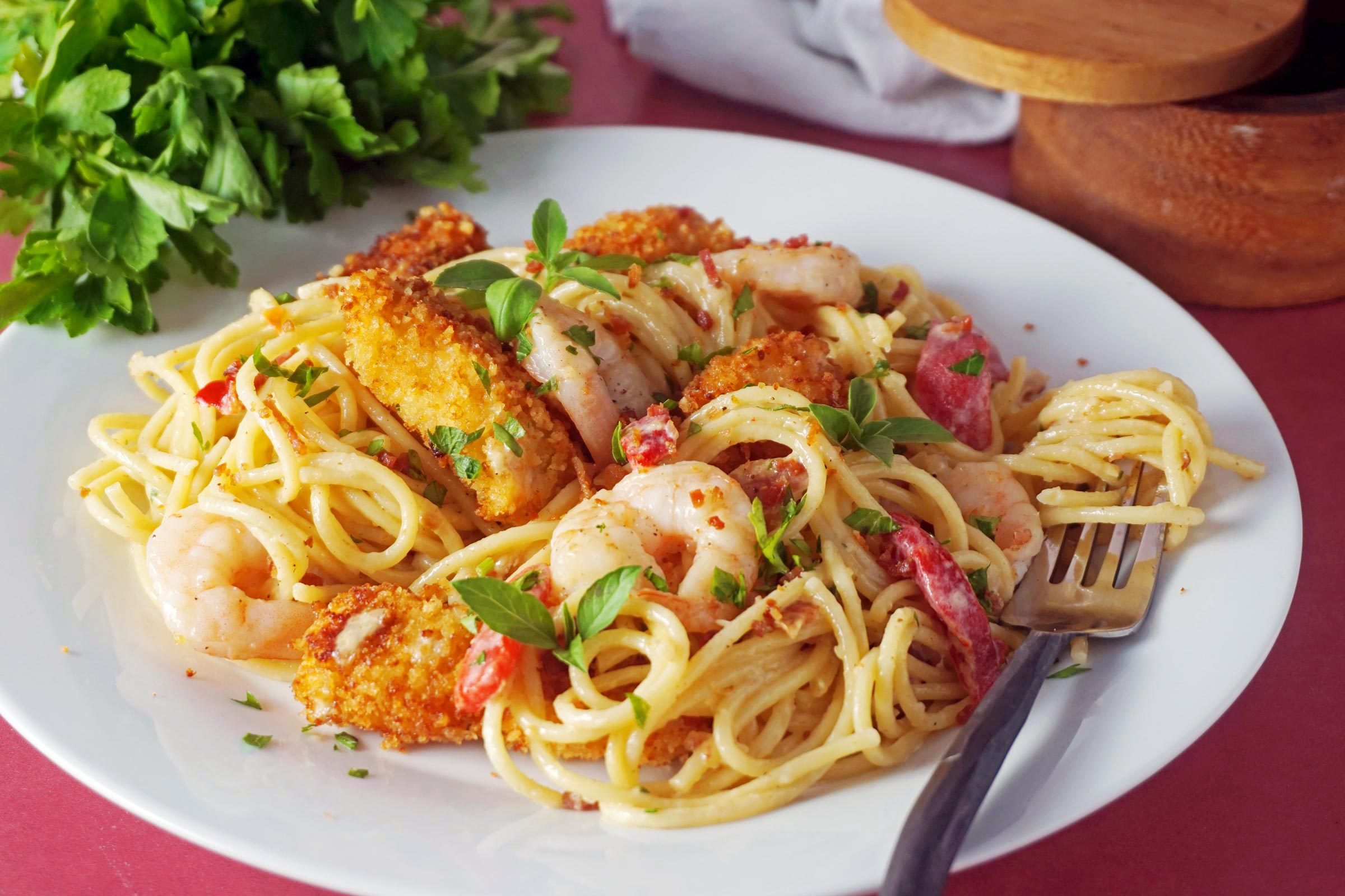 shrimp carbonara pasta on a white plate and a fork