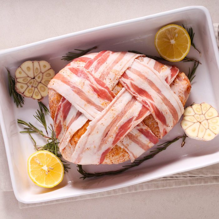 Raw turkey crown wrapped in bacon strips