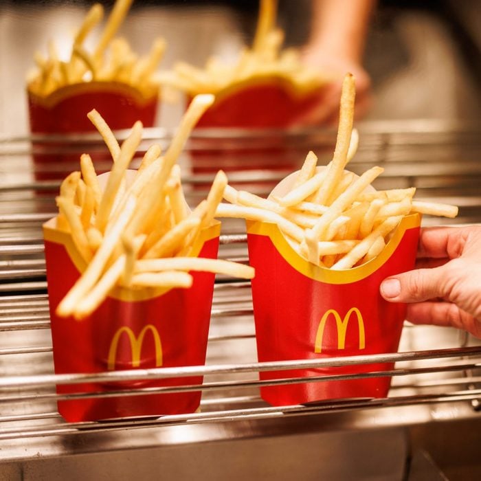 Employee grabs McDonald's Fries From Fryer Area in the Restaurant's Kitchen
