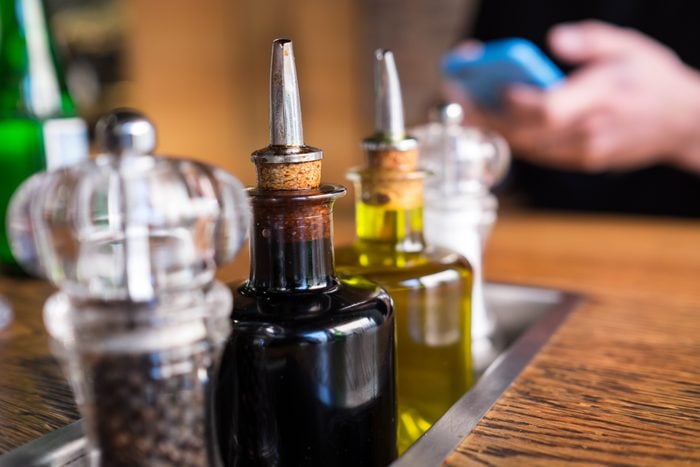 Close-up de garrafas de vinagre com saleiro e pimenteiro na mesa