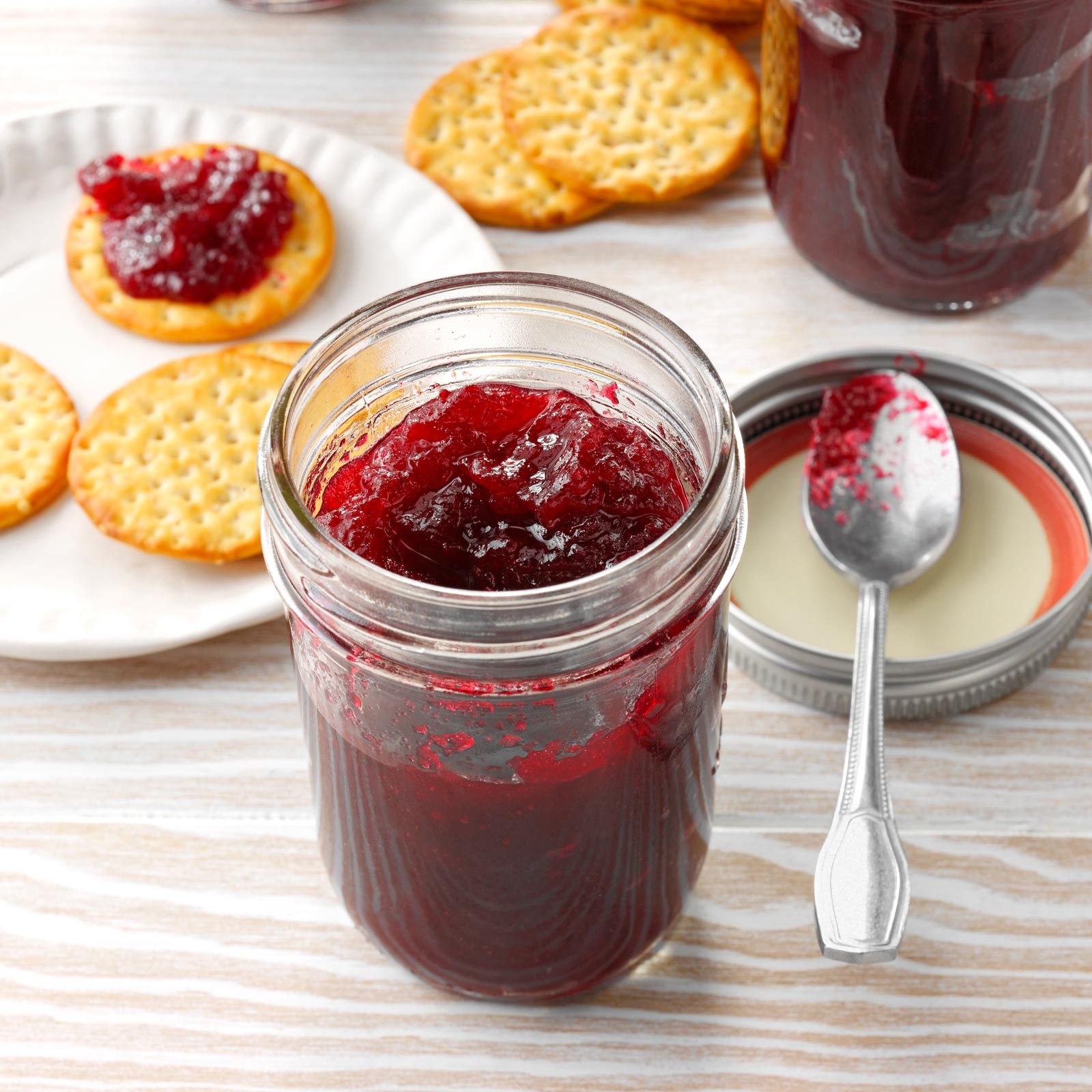mason jar of homemade jam with crackers and a spoon to the side