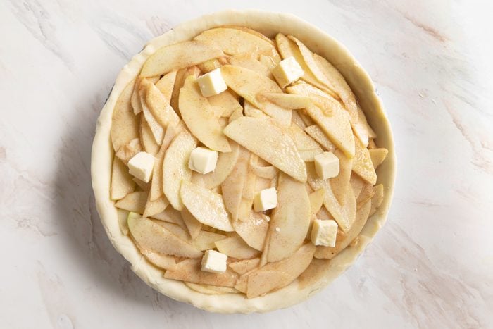filling a pie crust with sliced apples