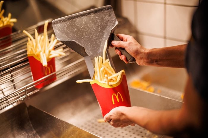 worker at McDonald's filling a cup of French fries