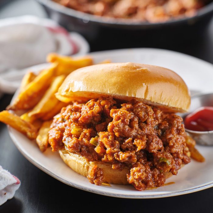 sloppy joe sandwich on plate with french fries and ketchup