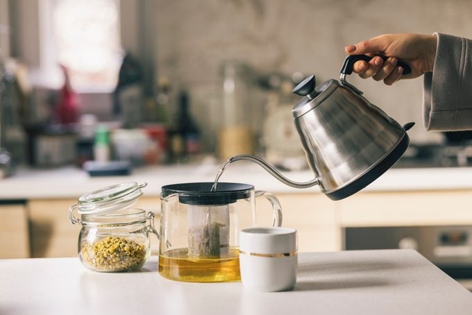 Hand of a Woman Brewing Chamomile Tea