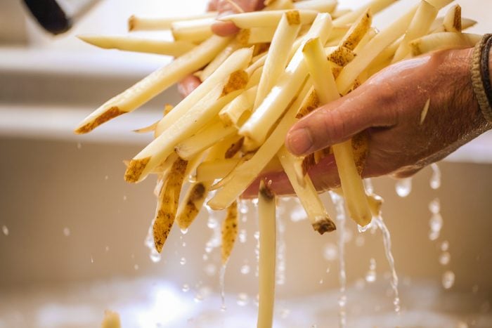 Close-up Of Person Rinsing Cut French Fries