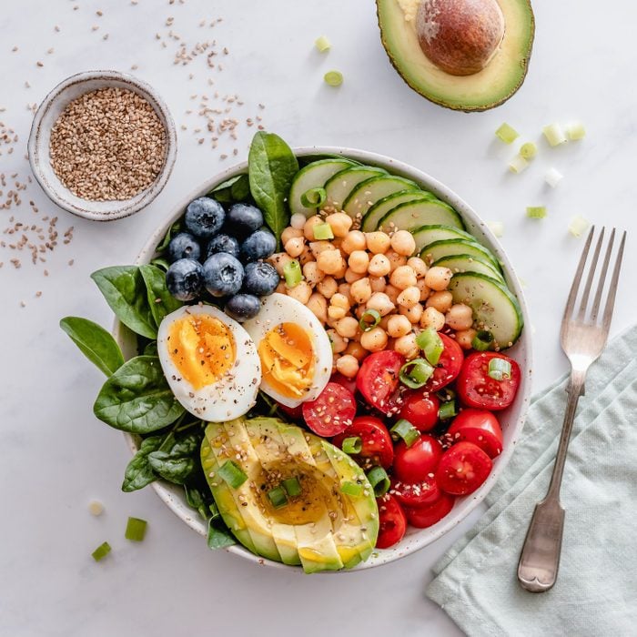 Buddha bowl with avocado, egg, chickpeas, tomato, cucumber, spinach and blueberries