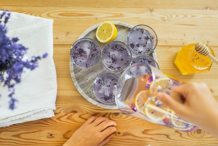 Honey, glasses with ice, lemon juice and lavender cocktail on kitchen table.