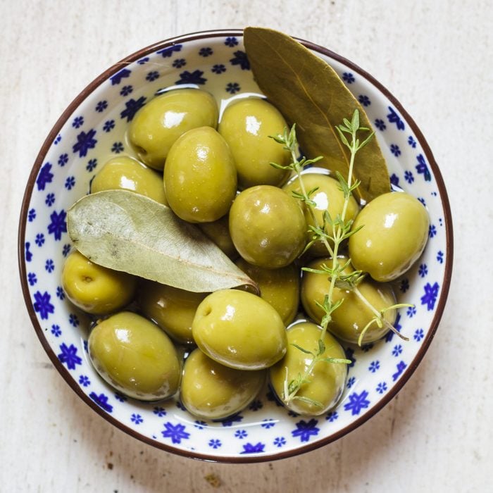 green olives in bowl with thyme and bay leaf