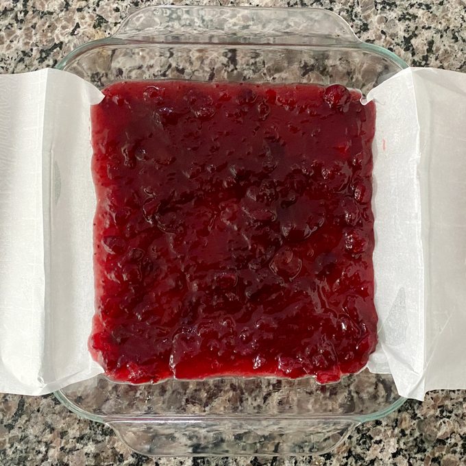 glass baking dish lined with parchment paper and filled with a thin layer of cranberry