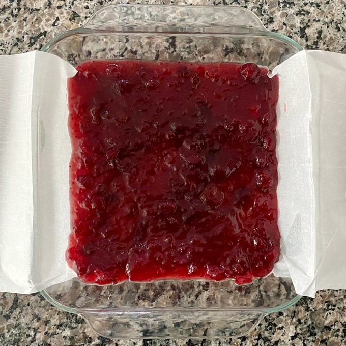 glass baking dish lined with parchment paper and filled with a thin layer of cranberry