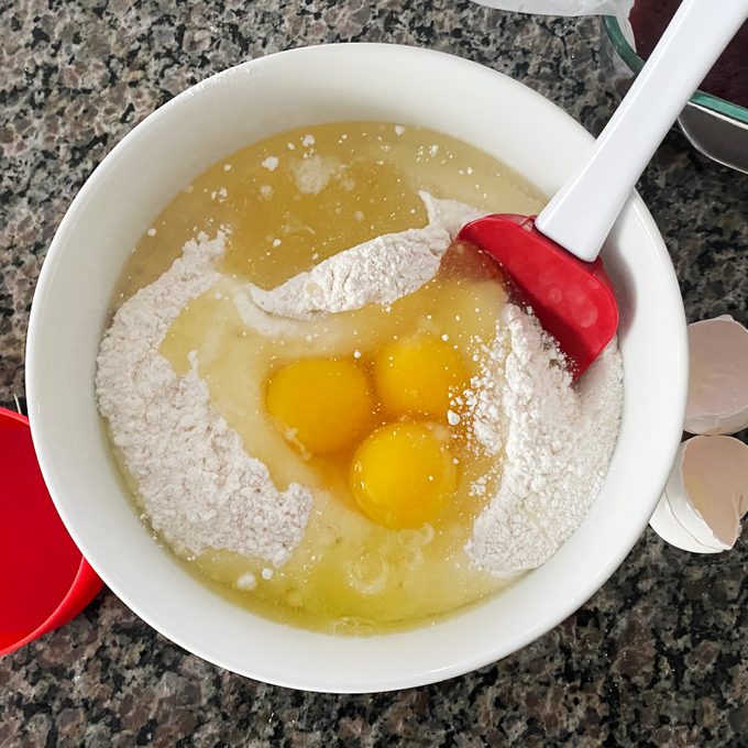 eggs and cake mix in a bowl being mixed with a rubber spatula