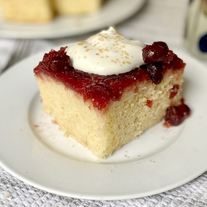 Square slice of Cranberry Duff topped with whipped cream