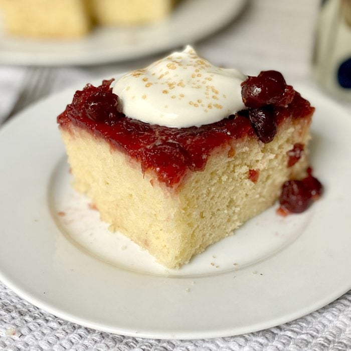 Square slice of Cranberry Duff topped with whipped cream