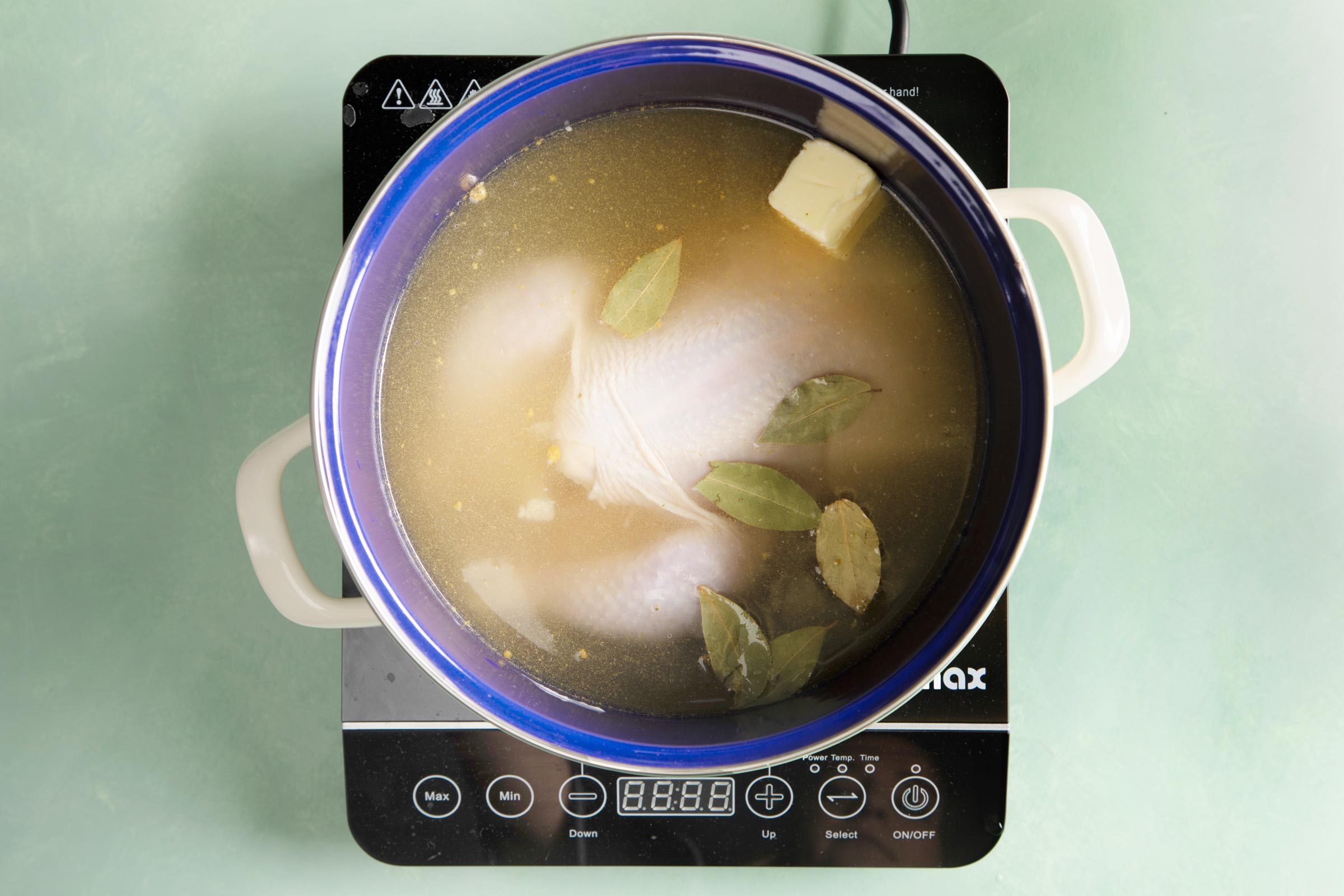 boiling a chicken in a large stock pot on a hot plate