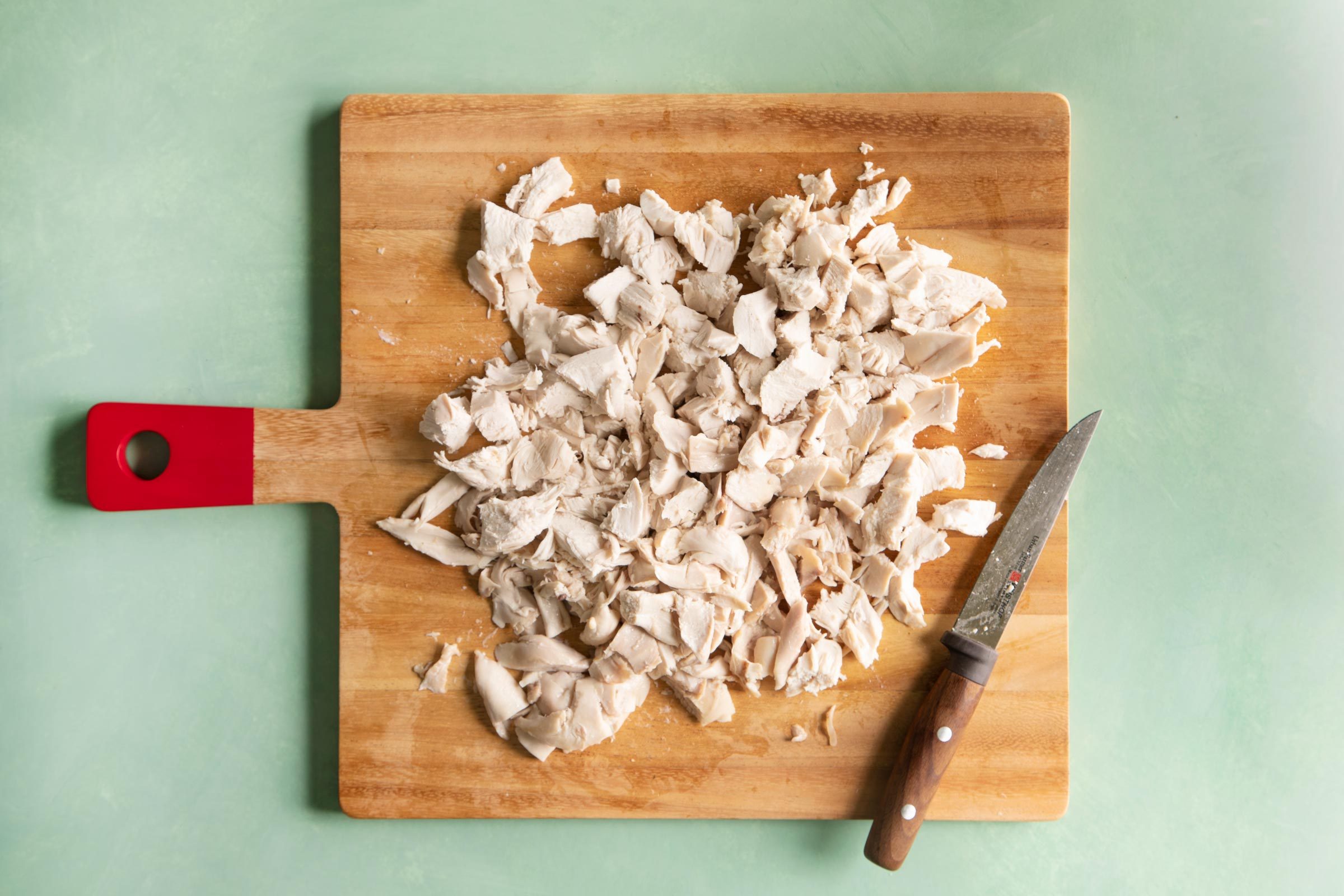 small pieces of chicken on a wooden cutting board on a green table