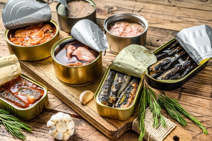 Various Canned Fish And Seafood in Metal Cans on Wooden Background