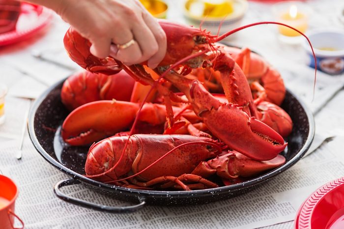 Person taking lobster from plate