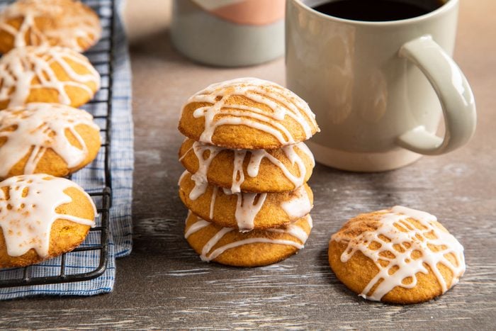 Gluten-Free Pumpkin Cookies in a stack, next to a cooling rack with more cookies and a cup of coffee