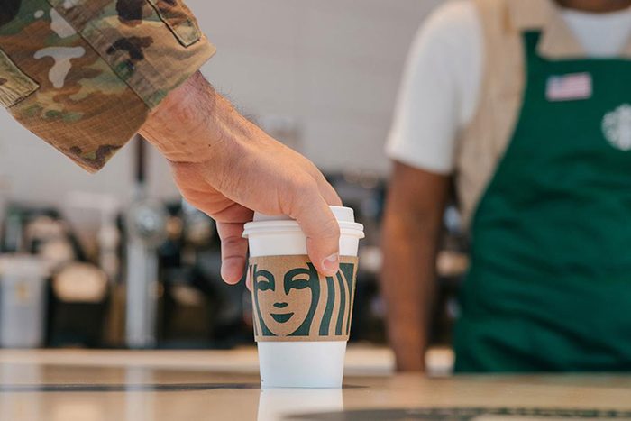 anonymous veteran hand picking up a free coffee at starbucks on veterans day