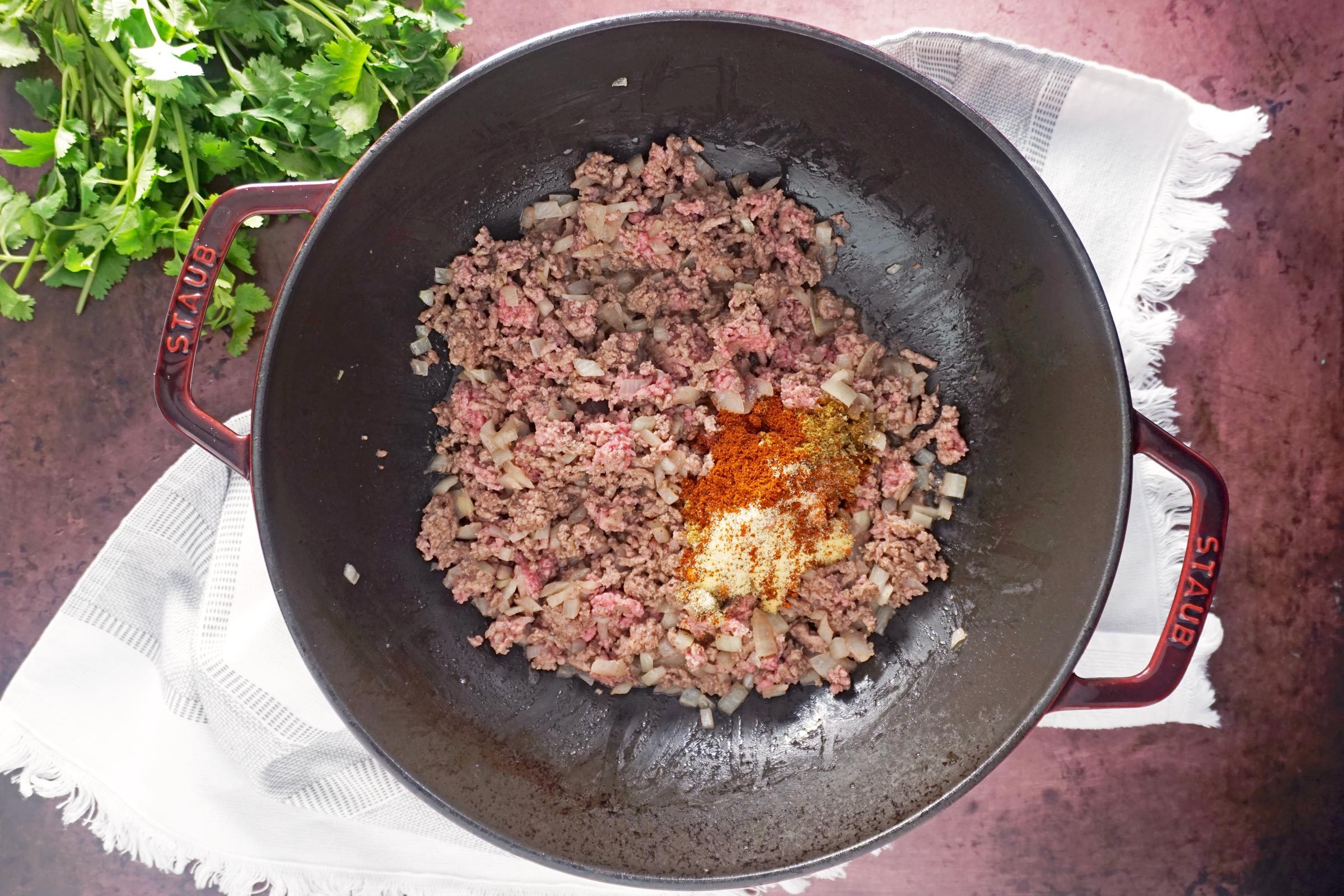 adding apices to browned beef and sautéed onions in a pan