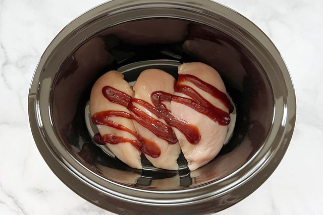 raw chicken with bbq sauce in a crock pot