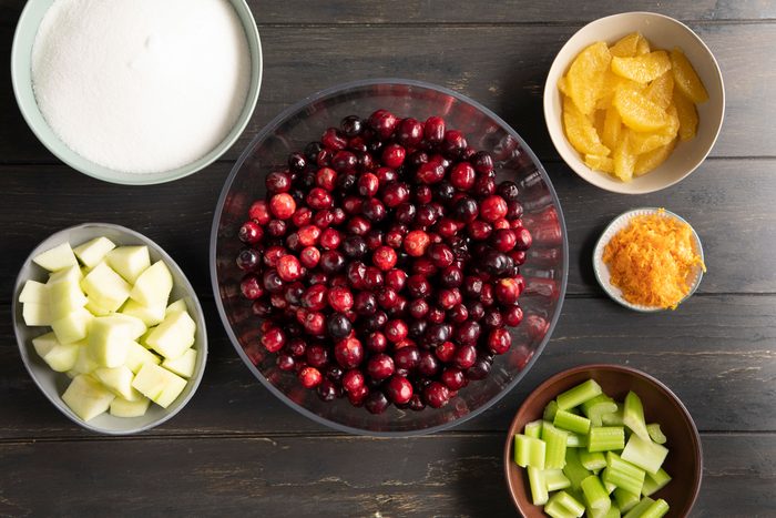 Cranberry Relish ingredients laid out in bowls on a dark wood background