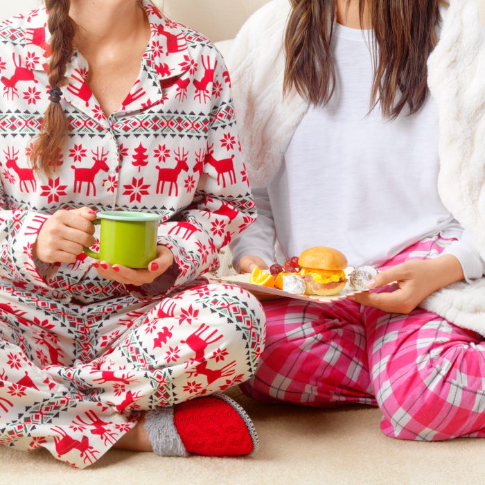 two people wearing holiday pajamas sitting on the ground