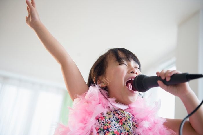 Filipino girl singing karaoke in living room