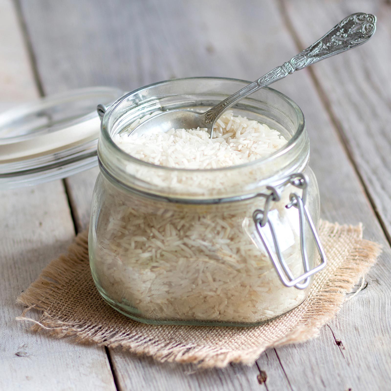 Rice In A Glass Jar on a burlap square on a gray wooden background
