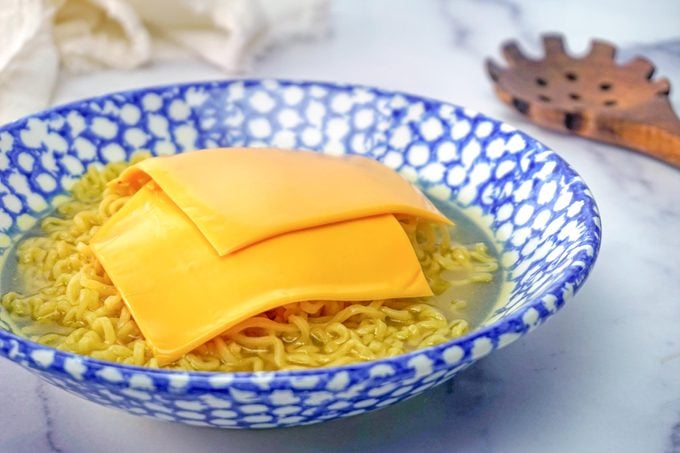 Cheesy Ramen noodles in a bowl with american cheese singles slices on top