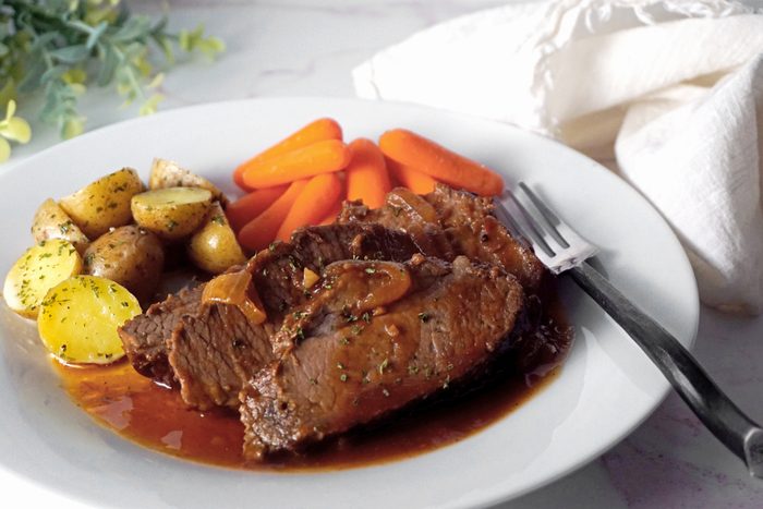 brisket on a plate with potatoes and baby carrots