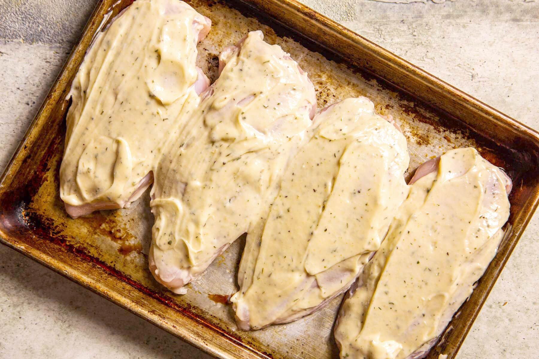 raw chicken covered in ranch on a baking sheet before baking