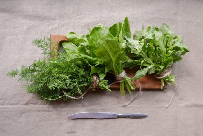 fresh greens on a wooden board with a knife on a linen tablecloth