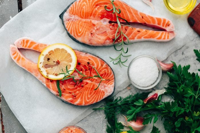 two raw pieces of salmon prepared with with lemons and herbs before being cooked