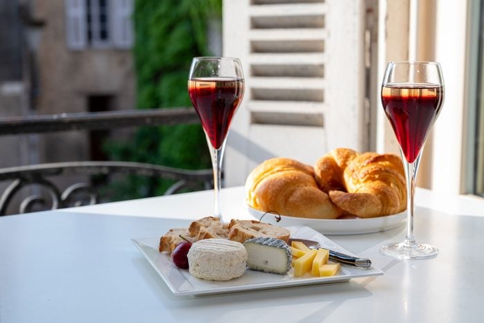 Kir Royale french cocktails rest on a table with croissants and a view of an old french village