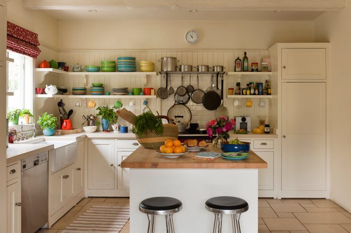 Barstools surround butchers island in white kitchen with colorful dishes