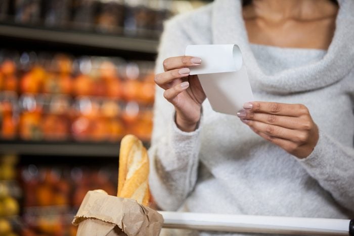 woman holding receipt in grocery section of supermarket