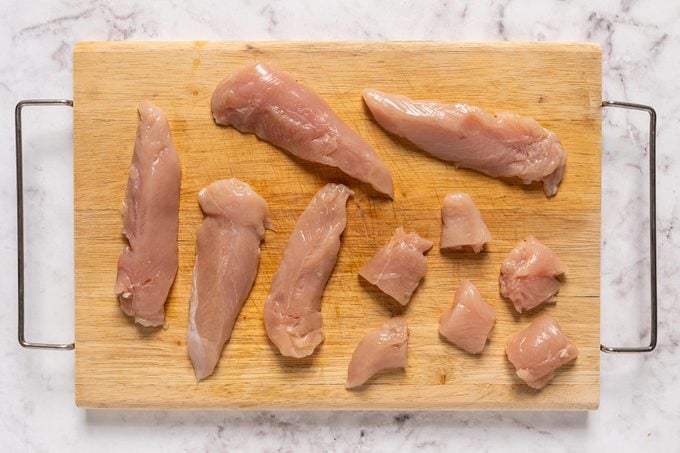 Pieces of chicken breast on chopping board