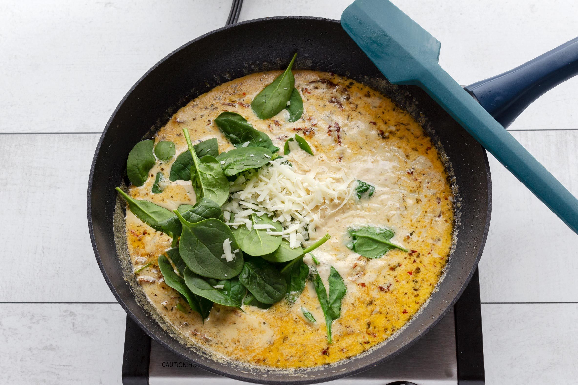 Adding the cream, spinach and cheese to the marry me chicken sauce in a skillet