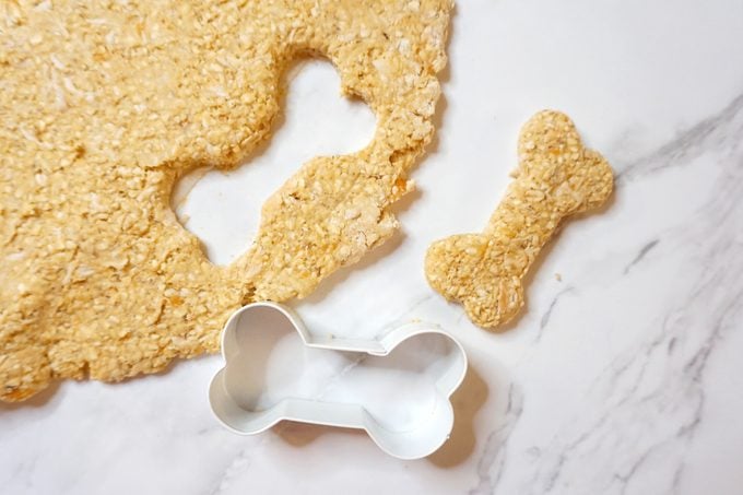 using a bone shaped cookie cutter to cut out homemade chicken dog treats