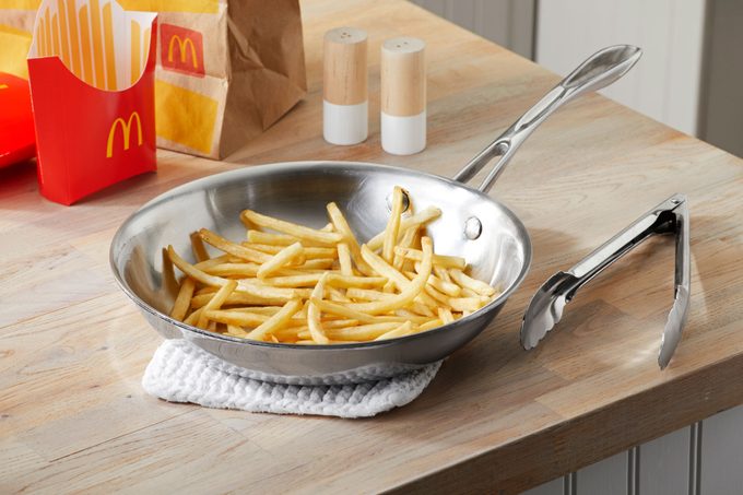 mcdonalds fries in a silver pan on a pot holder on a wood countertop