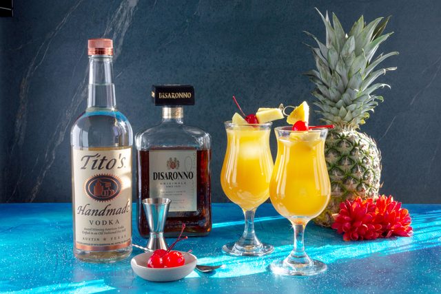 Cuban Breeze Cocktail with bottles of alcohol and a pineapple