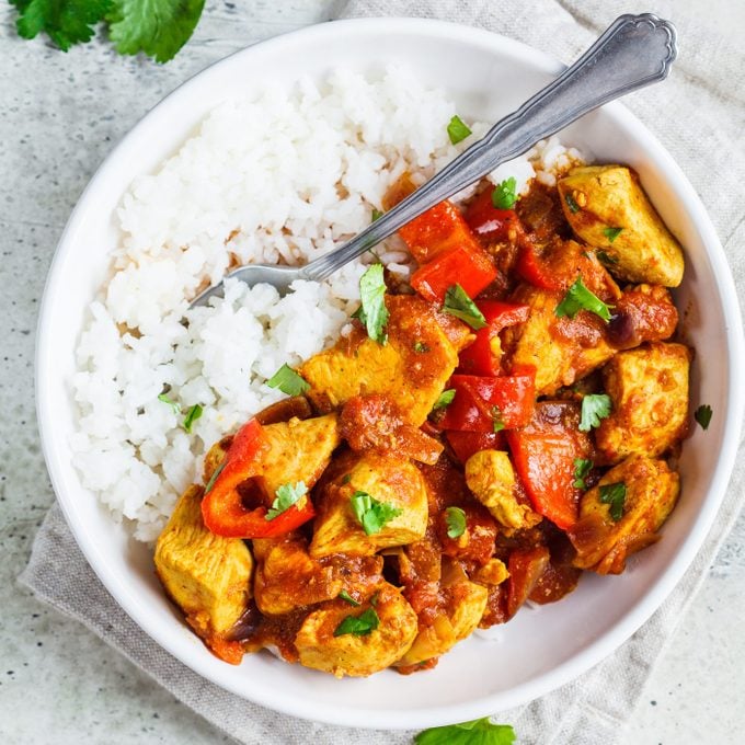 Jalfrezi chicken with rice in white bowl, top view, copy space. Traditional indian cuisine concept.