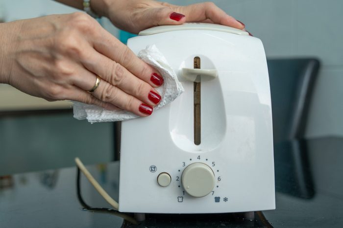 hand wiping an electric toaster
