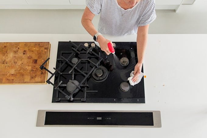 Overhead view of a woman cleaning a stove in a kitchen