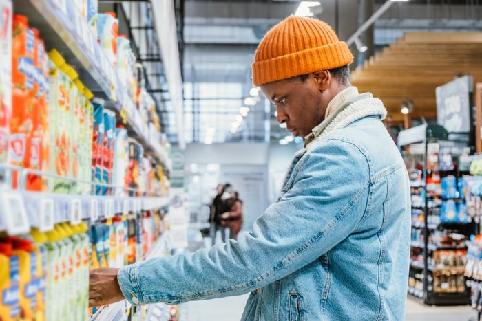 Thoughtful African-American man chooses juice at store rack