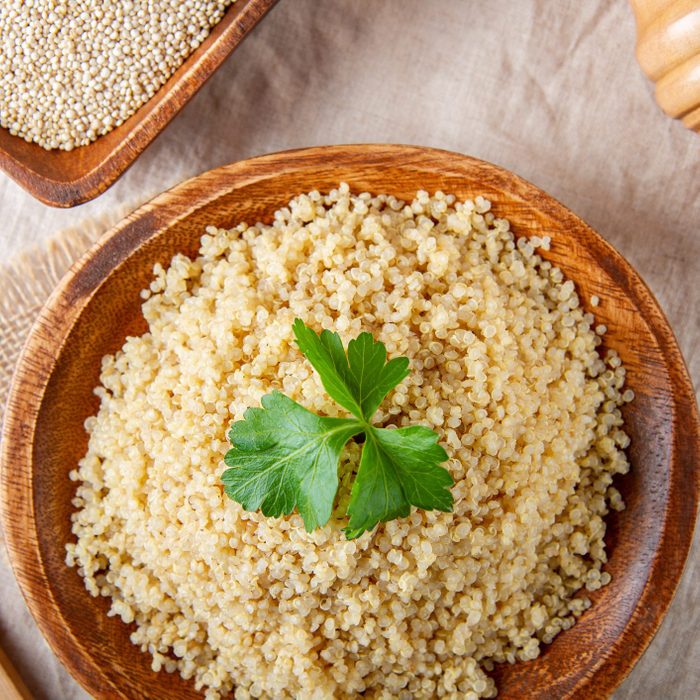 Cooked quinoa in a wooden plate on the table, top view.