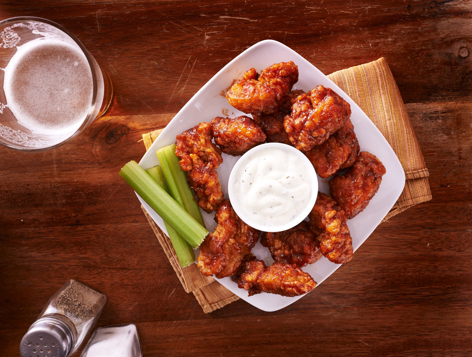 bbq buffalo chicken wings with beer ranch and celery on a wooden table