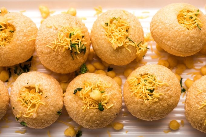 Stuffed Sev Puri is a popular Indian roadside chat item, served in a white plate. Top view, selective focus